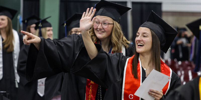 Girls smiling and waving at graduation.