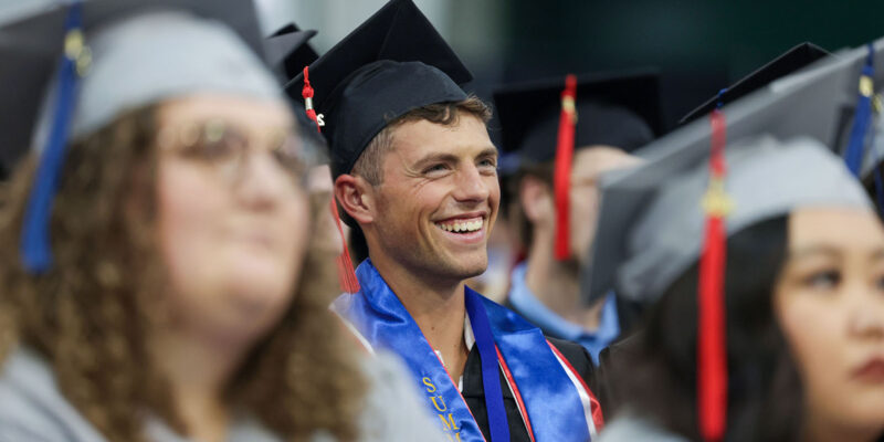 Boy smiling within group of graduates.