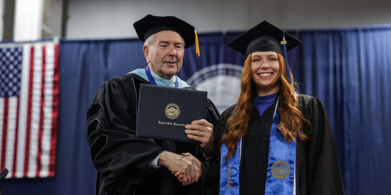 President of university shaking hands with female graduate.