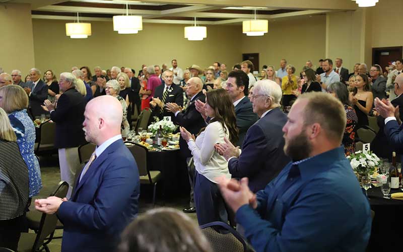 group of people standing and clapping at banquet