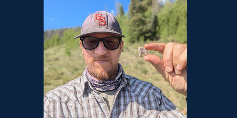 Dr. Andrews holds a fragment of a Folsom stone projectile point recovered from excavations near a 12,500-year-old hearth.