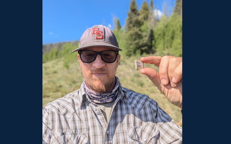 Dr. Andrews holds a fragment of a Folsom stone projectile point recovered from excavations near a 12,500-year-old hearth.