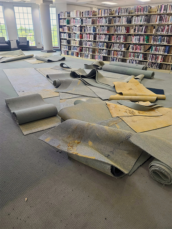 Old carpeting pulled on and laying on the floor in library