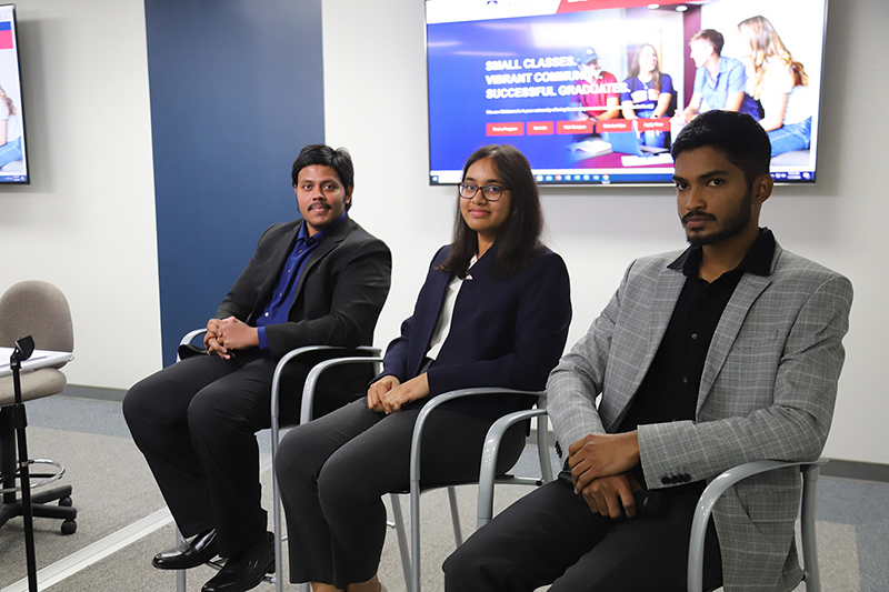 Two men and a woman sitting in chairs as panelists