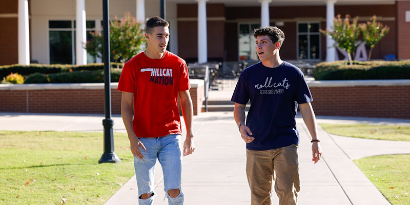 Two boys walking and talking across college campus