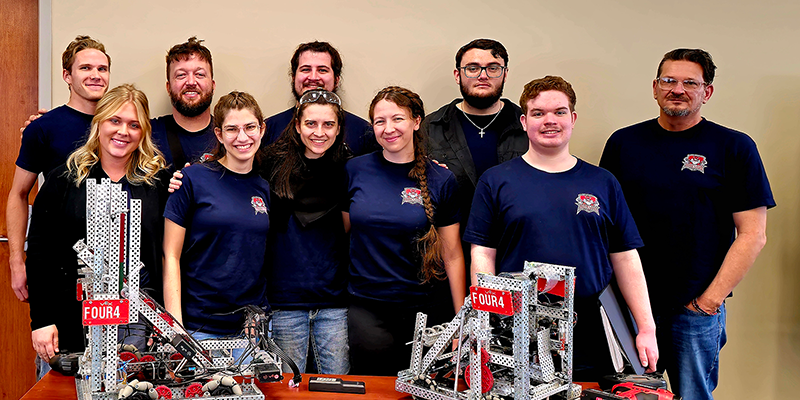 Group standing behind table with robots