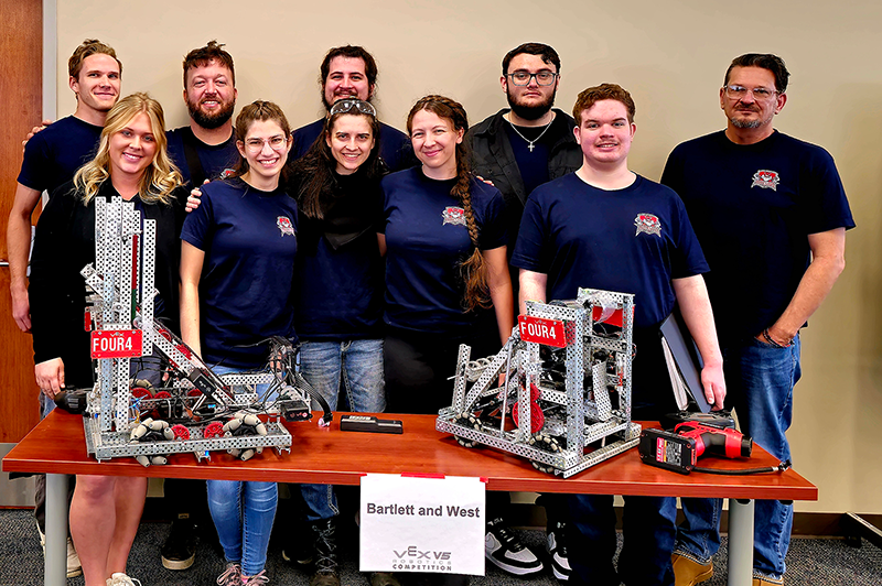 Group standing behind table with robots