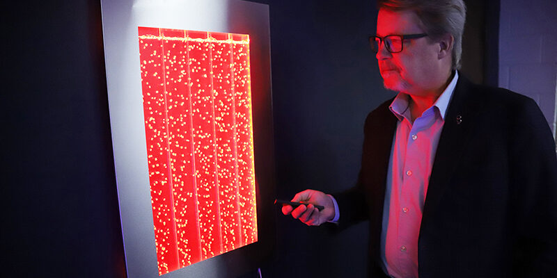 A man stands nexts to an illuminated sensory board