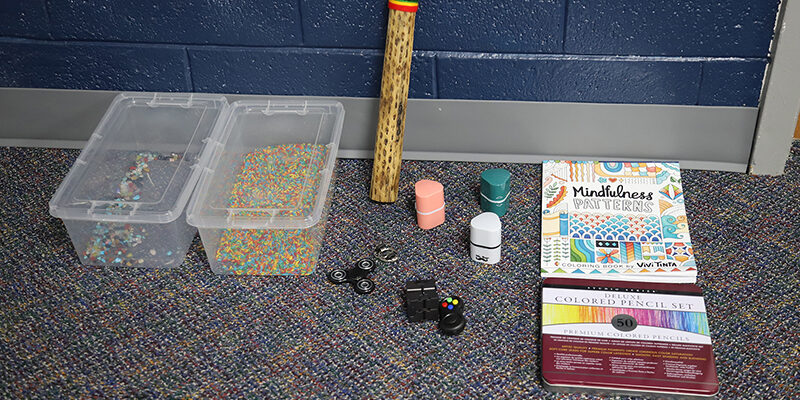 Multiple items, including a book and colored pencils, on the floor of the RSU sensory room.