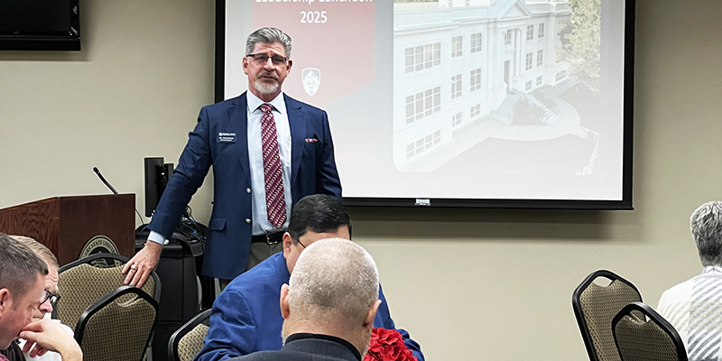 Dr. Mark Rasor stands and speak to a room full of people