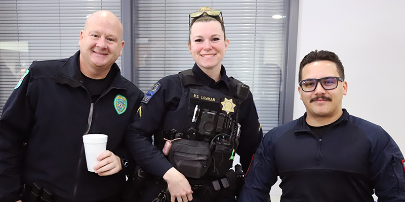 Two male and one female law enforcement officers smile and pose.