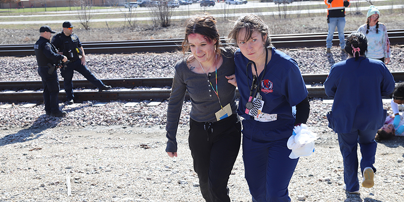 A female RSU nursing students walks with her arm around another female student, who is playing a "victim" during the mock disaster drill March 7.