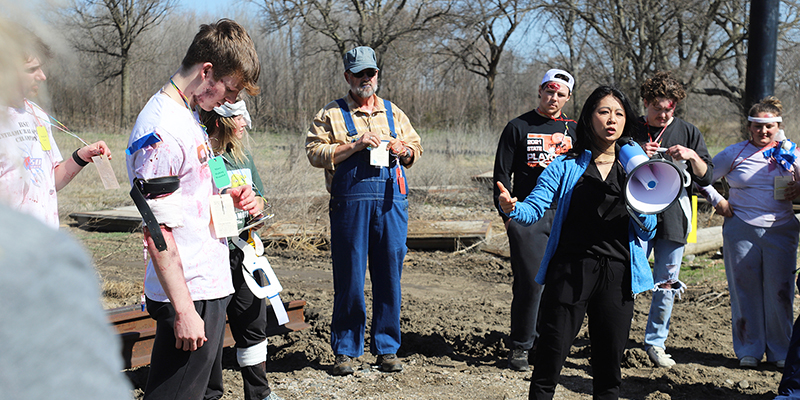 A female nursing professor addresses a crowd of students outside during a mock disaster drill.